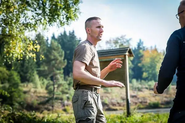 Zwei Personen stehen im Gespräch, eine Handbewegung ist sichtbar