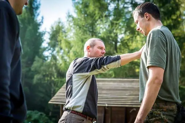 Zwei Personen stehen im Gespräch, eine Person berührt die andere am Arm