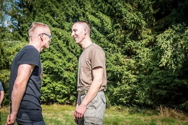 Zwei Personen stehen sich gegenüber und unterhalten sich in einer grünen Umgebung