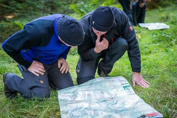 Zwei Personen studieren eine Karte auf dem Boden im Wald