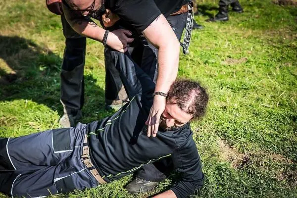 Zwei Personen üben eine Kontrolle am Boden auf einer Wiese aus