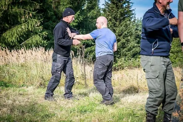 Zwei Personen üben eine Selbstverteidigungstechnik auf einer Wiese