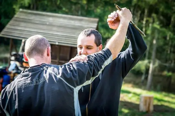 Zwei Personen üben eine Selbstverteidigungstechnik mit einem Stock