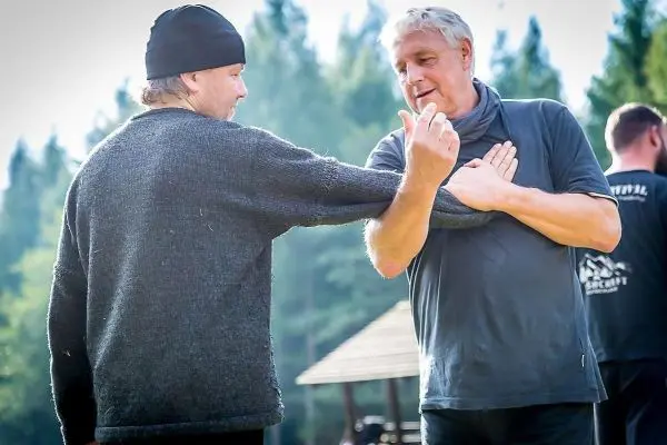 Zwei Personen üben eine Technik im Nahkampf, einer demonstriert eine Armbewegung