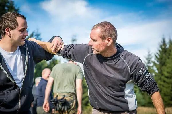 Zwei Personen üben eine Technik zur Armkontrolle im Freien