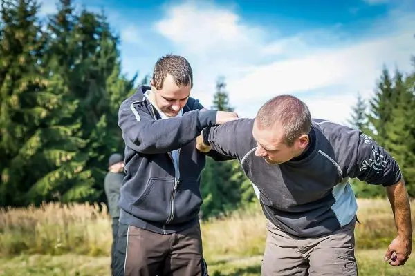 Zwei Personen üben eine Technik zur Kontrolle des Gegners im Freien