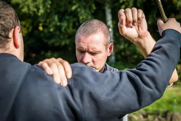 Zwei Personen üben eine Technik zur Selbstverteidigung im Freien