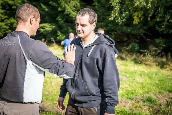 Zwei Personen üben eine Technik zur Selbstverteidigung im Freien