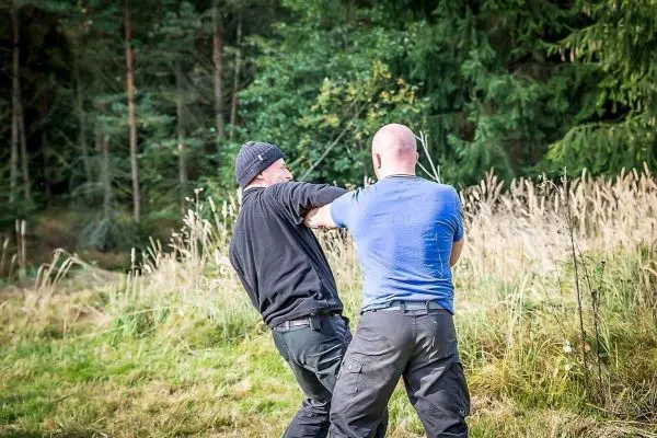 Zwei Personen üben eine Technik zur Selbstverteidigung im Freien