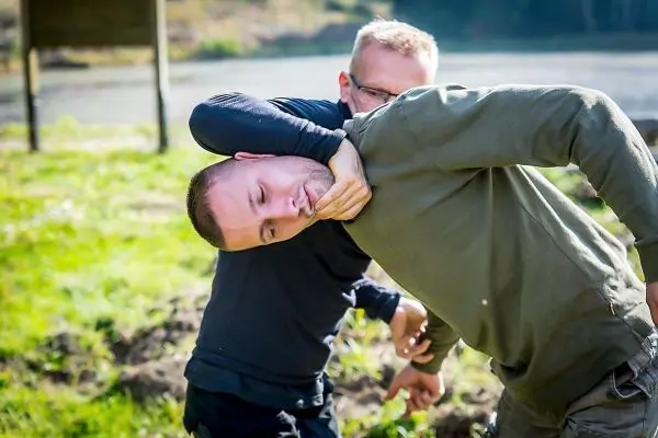 Zwei Personen üben einen Haltegriff im Freien aus