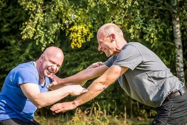 Zwei Personen üben einen körperlichen Griff im Freien