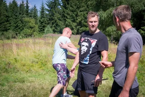 Drei Personen stehen in einem Feld, eine Person führt eine Bewegung aus