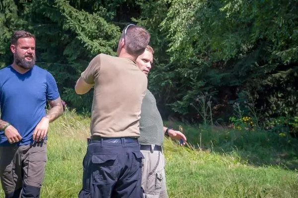 Drei Personen stehen in einer Wiese und führen ein Gespräch