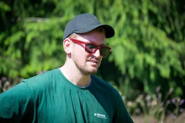 Ein Mann trägt ein grünes T-Shirt, eine schwarze Kappe und Sonnenbrillen