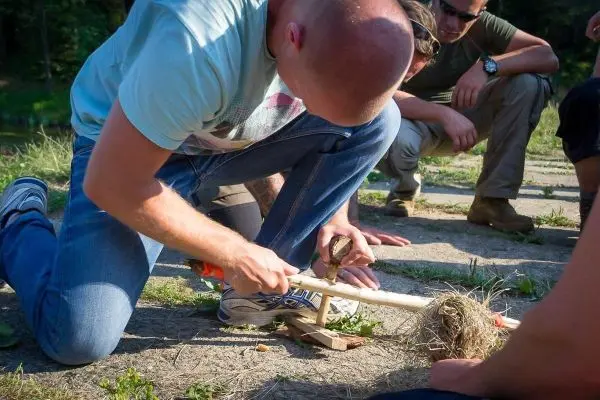 Feuerbohrer wird mit einem Holzstück und Zunder verwendet