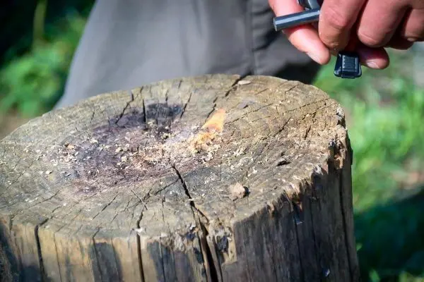 Feuerstahl erzeugt Funken auf einem Holzstück