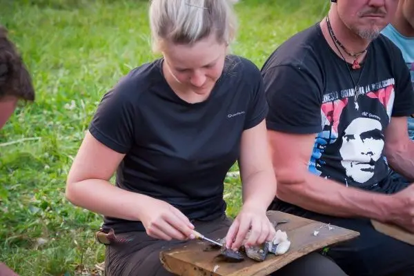 Frau filetiert Fisch auf einem Holzbrett im Freien