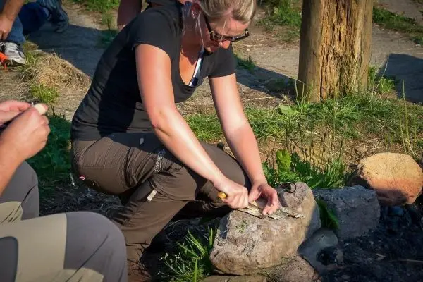 Frau filetiert Fisch auf einem Stein mit einem Messer