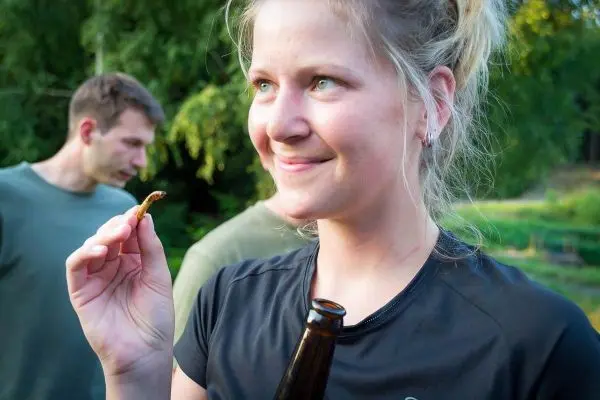 Frau hält einen Snack in der Hand und lächelt, Bierflasche in der anderen Hand