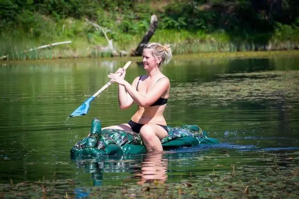 Frau paddelt auf einem improvisierten Floß im Wasser