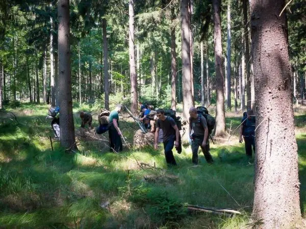 Gruppe von Personen erkundet den Wald mit Rucksäcken beim Überlebenstraining