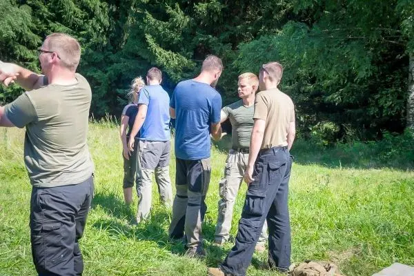 Gruppe von Personen steht im Freien und spricht miteinander beim Überlebenstraining