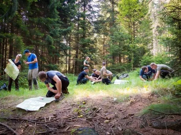 Gruppe von Personen studiert Karten im Wald beim Überlebenstraining