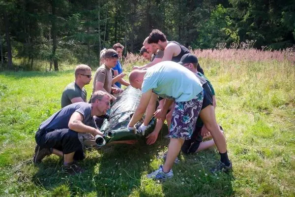 Gruppierung hebt eine improvisierte Trage an, um eine Person zu transportieren