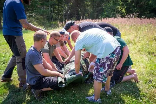 Gruppierung hebt improvisierte Trage mit einer Person darin an