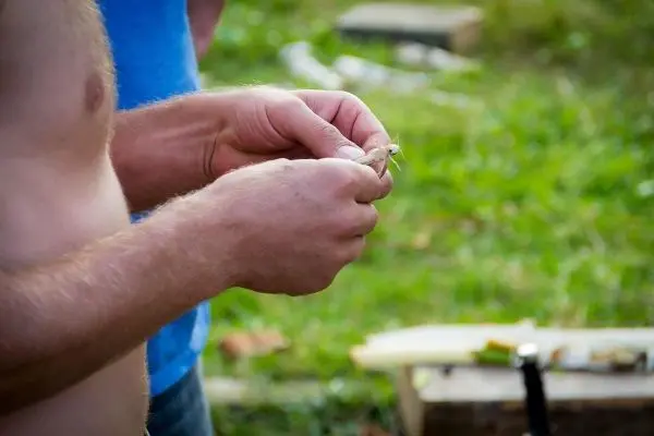 Hände halten ein kleines Stück Holz zum Schnitzen