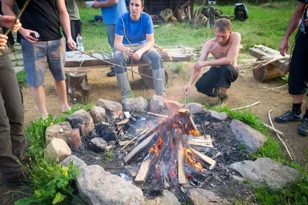 Kleine Flamme brennt in einem Steinkreis, Holzscheite liegen daneben