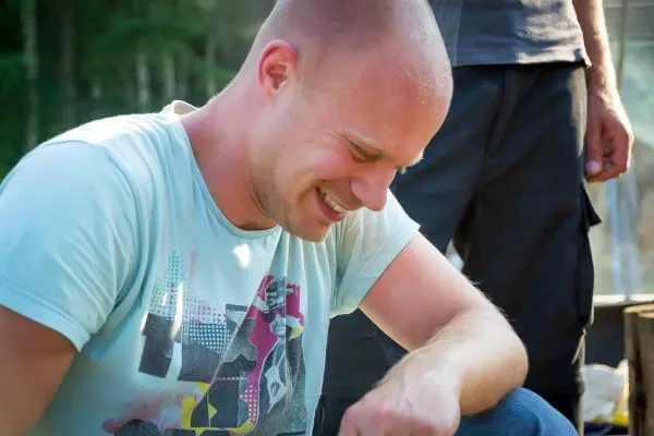 Lächelnde Person beugt sich über einen Tisch im Freien