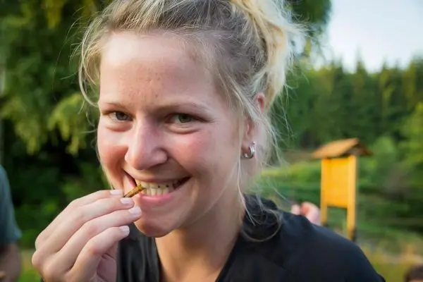 Lächelnde Person hält einen kleinen Snack zwischen den Zähnen