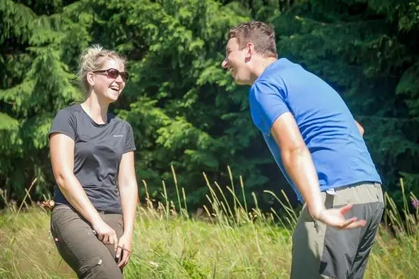 Lächelnde Personen stehen in einer Wiese und unterhalten sich fröhlich