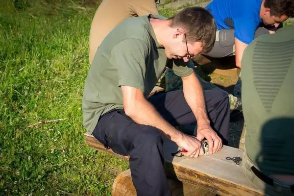 Mann bearbeitet Holzstück mit einem Messer auf einer Holzbank