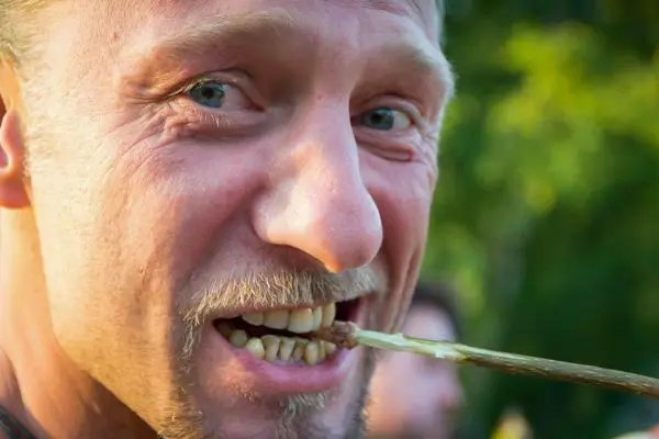 Mann beißt in einen Stock und lächelt dabei