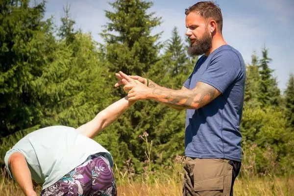 Mann demonstriert eine Technik zur Kontrolle des Arms eines anderen Mannes im Freien