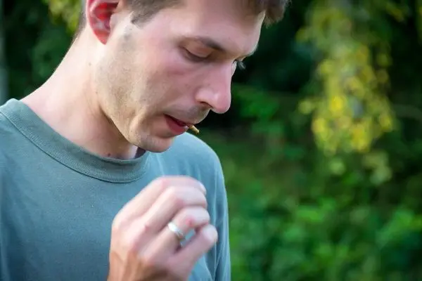 Mann hält einen kleinen Gegenstand zwischen Daumen und Zeigefinger