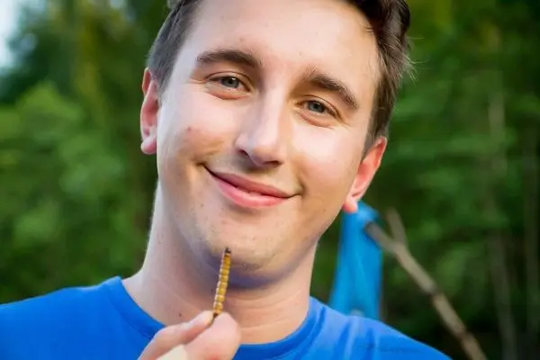 Mann hält einen kleinen Stock in der Hand und lächelt