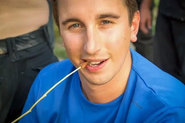 Mann hält einen Stock im Mund und lächelt in die Kamera