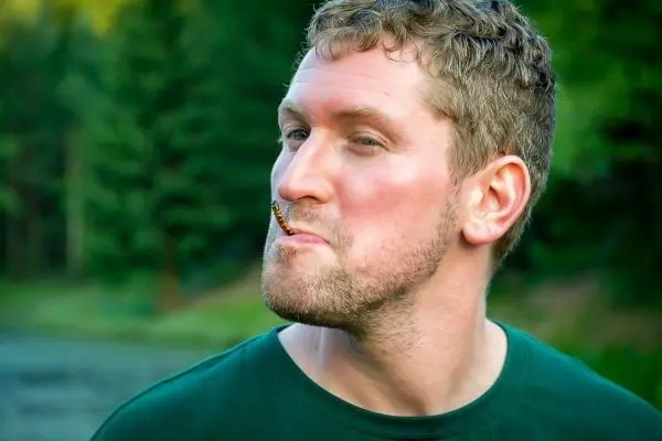 Mann mit einem Insekt im Mund und schelmischem Gesichtsausdruck