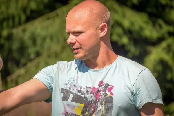 Mann mit kurzem Haar zeigt mit der Hand in Richtung eines Objekts