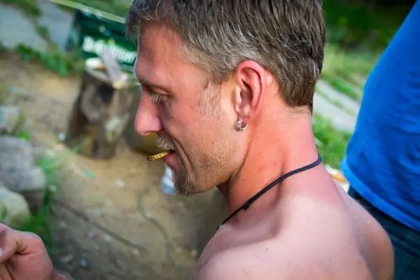 Mann mit Zigarette im Mund betrachtet ein Objekt in der Hand