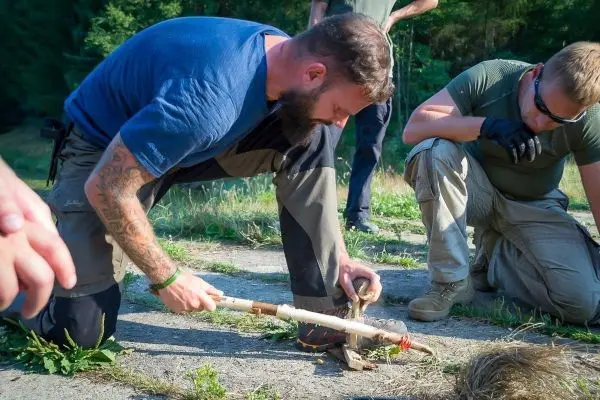 Mann nutzt Feuerbohrer-Technik zur Zundererzeugung auf dem Boden