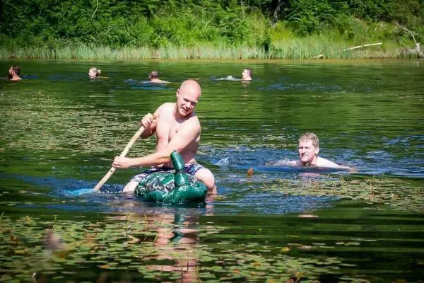 Mann paddelt mit einem Stock auf einem aufblasbaren Boot im Wasser