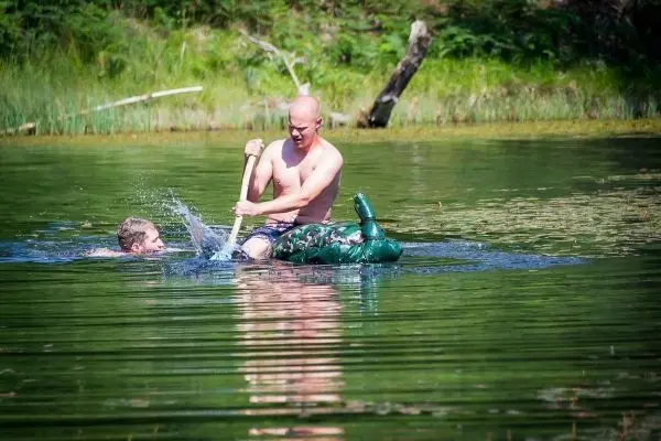 Mann paddelt mit einem Stock auf einem aufblasbaren Tier im Wasser
