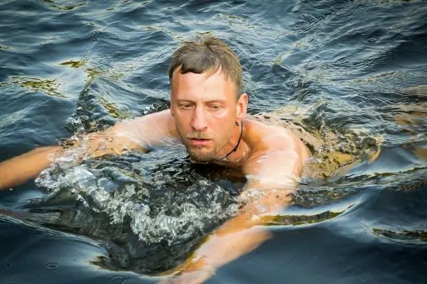 Mann schwimmt in einem Gewässer und bewegt die Arme durch das Wasser