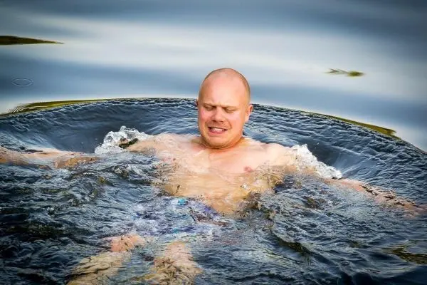 Mann schwimmt in einem Gewässer und spritzt Wasser um sich herum