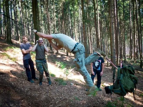 Mann überquert selbstgebaute Seilbrücke, während andere zuschauen