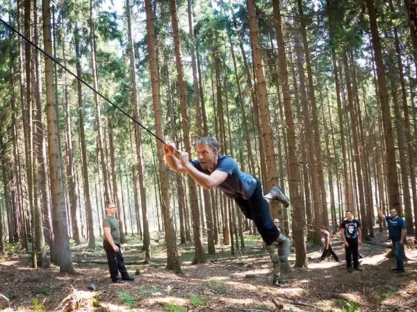 Mann überquert selbstgebaute Seilbrücke zwischen Bäumen im Wald